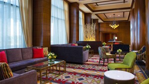 Un hall d’entrée spacieux, doté d’un grand canapé, de fauteuils, d’une table basse et d’un tapis à motifs.