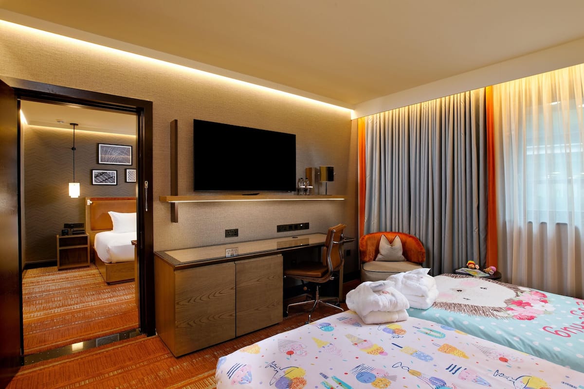 Una habitación de hotel con cama, escritorio, silla, televisión y espejo.