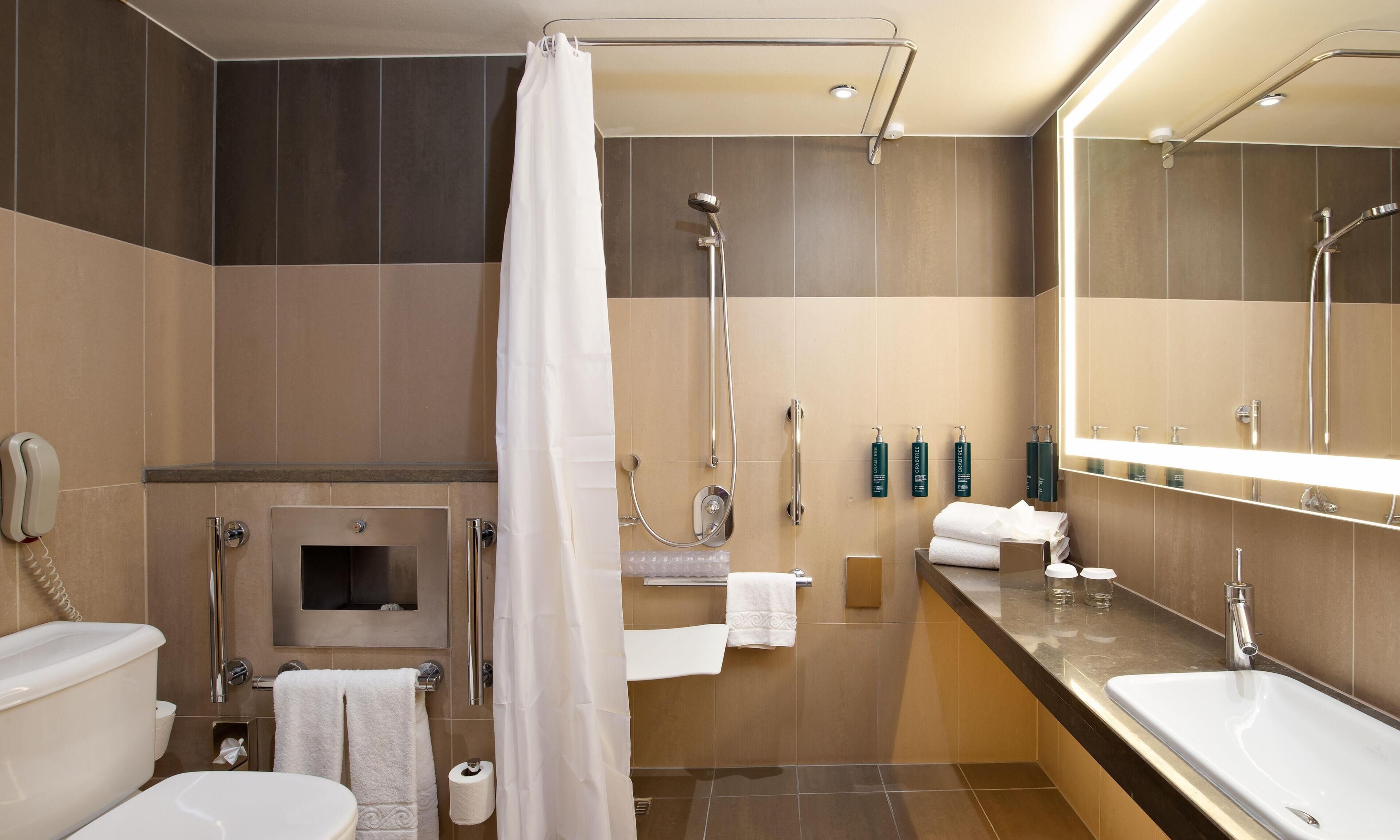 Un baño moderno con ducha, inodoro, lavamanos y espejo.