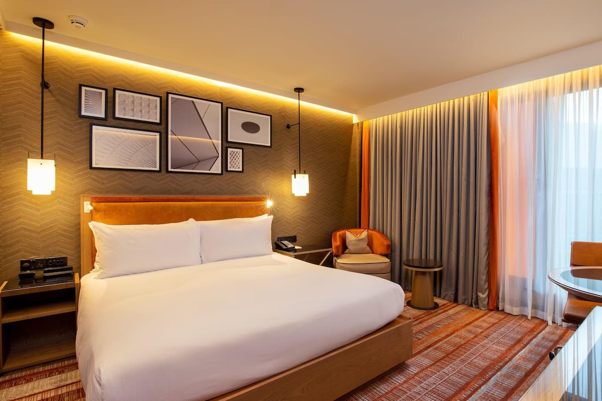 Habitación de hotel con una cama grande, un escritorio, una silla y vistas a la ciudad.