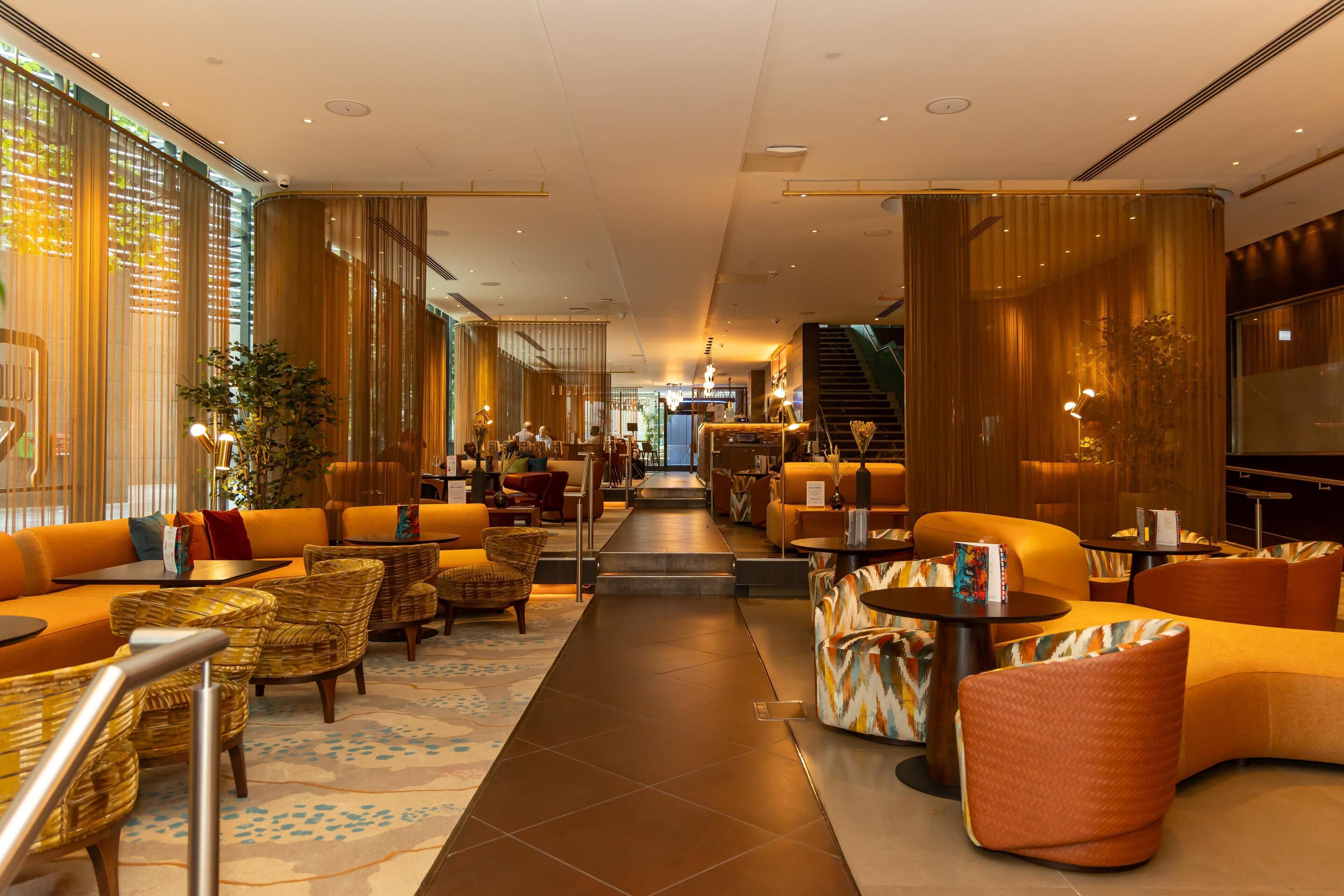 A hotel lobby with seating areas, a staircase, and a view of the interior.