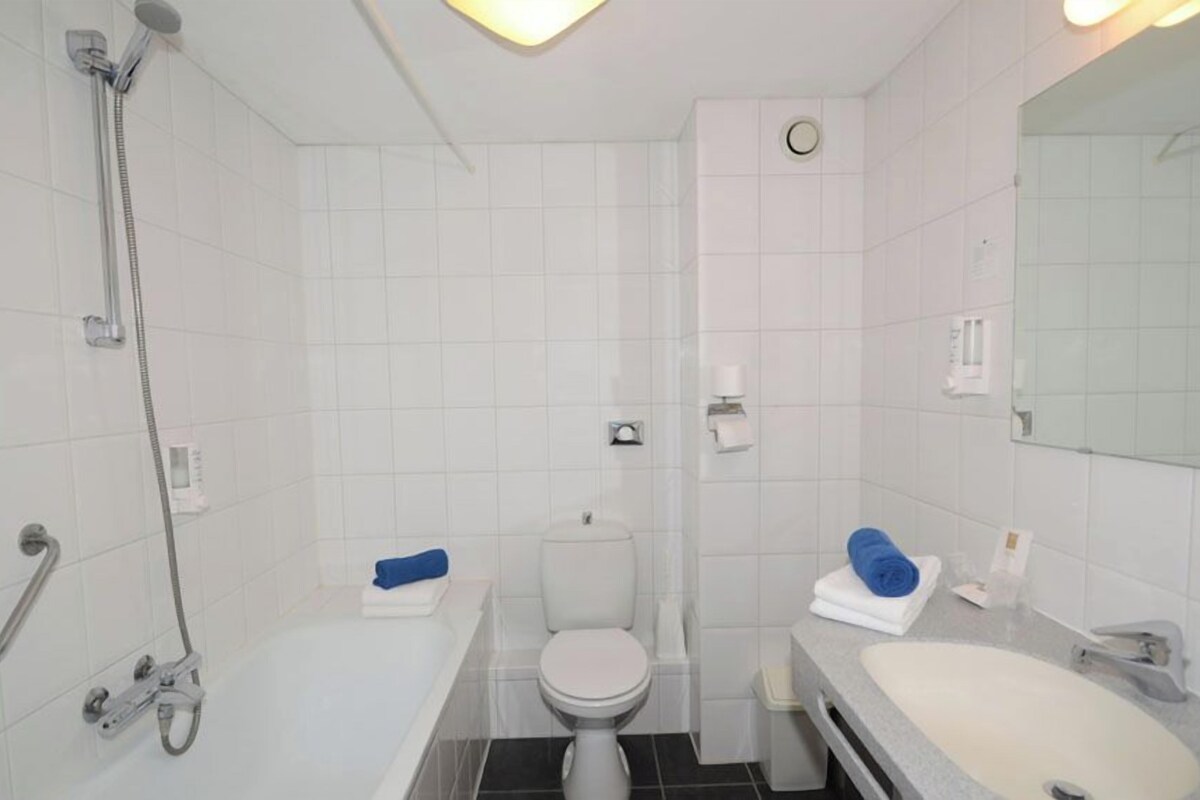 Un baño moderno con bañera, inodoro y lavamanos, todo en blanco.