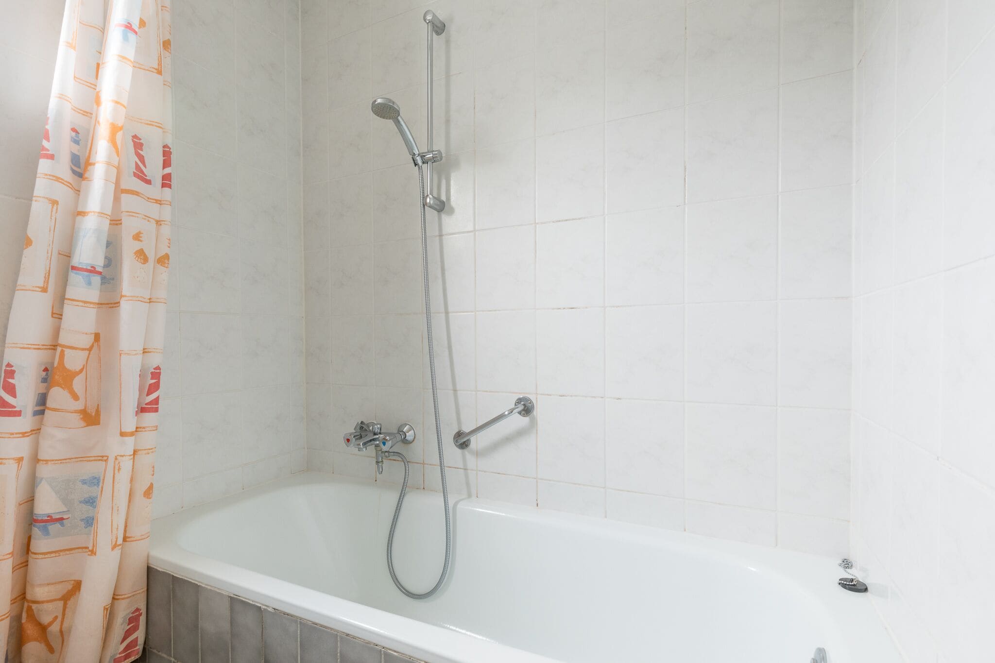 A bathroom with a bathtub, shower, and curtain.