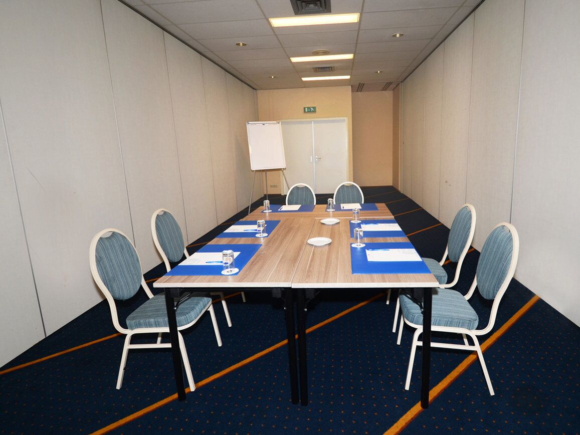 A conference room with a long table, six chairs, and a whiteboard.