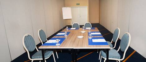 A conference room with a long table, six chairs, and a whiteboard.
