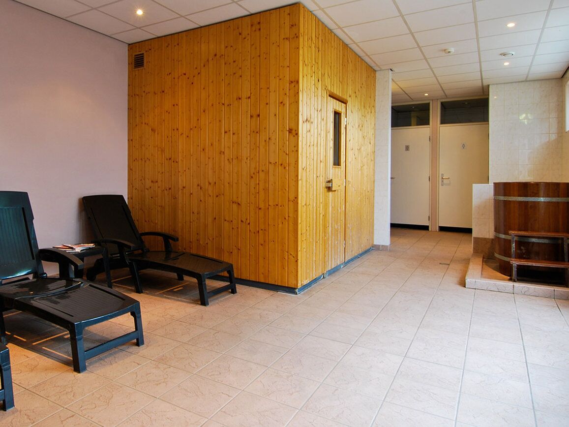 Une pièce avec une cloison en bois, deux chaises noires, une petite table et un meuble en bois.