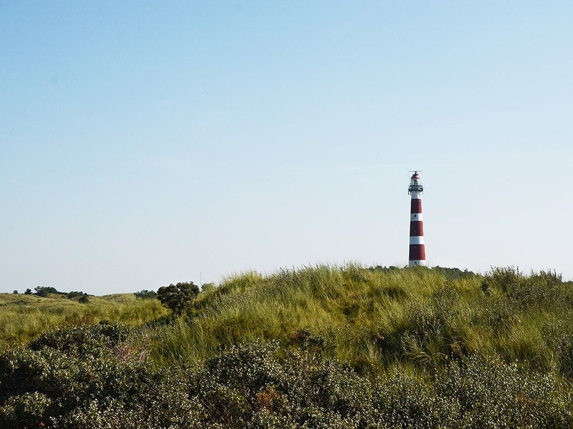 Un faro en una colina cubierta de hierba, bajo un cielo despejado.