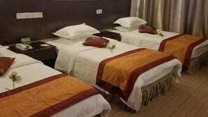 A hotel room with four single beds, each with a white and orange bedspread, and a wooden floor. - Yunnan Aviation Sightseeing Hotel (Lijiang)