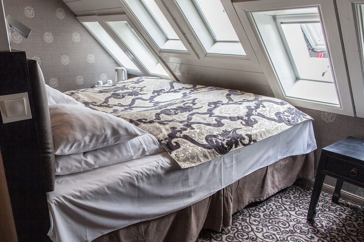 Un dormitorio con una cama, una mesita de noche y un ventanal con vista al cielo.