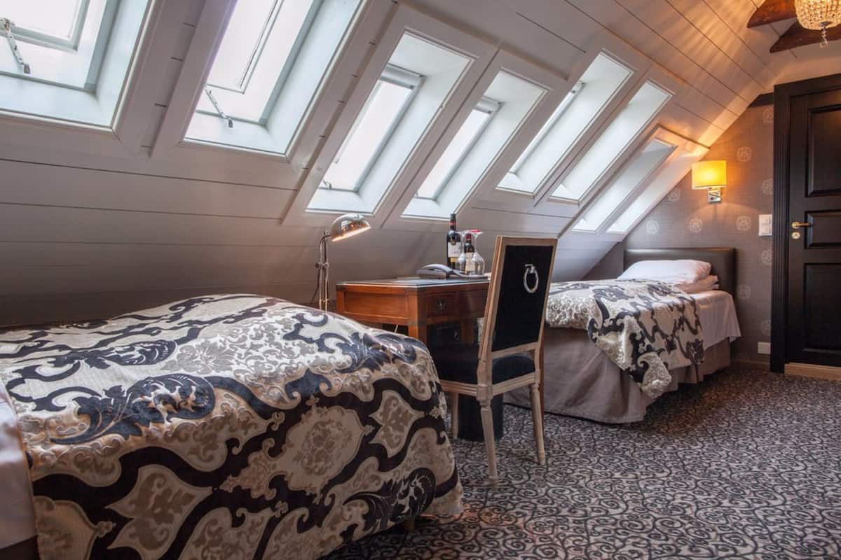 Habitación con dos camas, un escritorio y una silla. Cuenta con tragaluces en el techo.