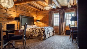 Quarto em estilo cabana de tronco com uma cama, uma escrivaninha e uma cadeira.