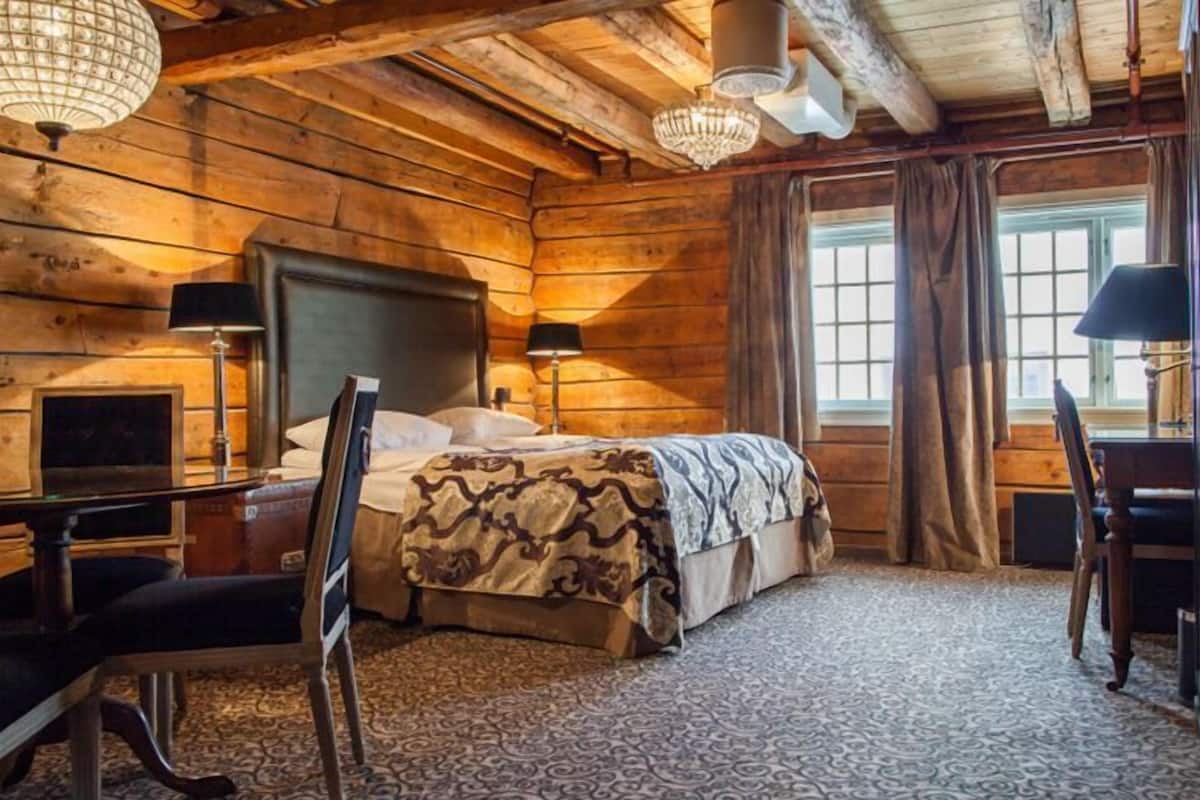 Una habitación tipo cabaña de troncos con una cama, un escritorio y una silla.