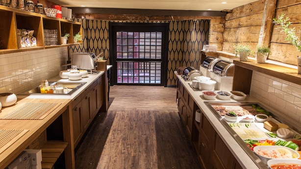 Cozinha moderna com armários de madeira, uma ilha central com alimentos e vista através de uma porta estampada.
