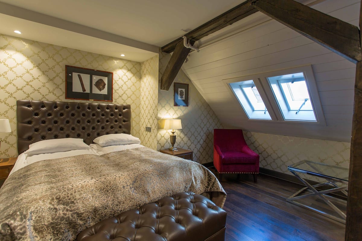 Un dormitorio con una cama grande, una silla roja y tragaluces.