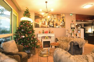 Una sala de estar acogedora con un árbol de Navidad, chimenea y asientos cómodos.