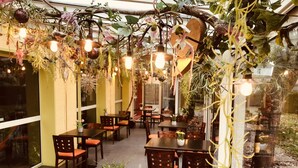 An indoor dining area with tables and chairs, hanging plants, and pendant lights. - Arc-En-Ciel Colmar (Colmar)