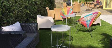 A patio with wicker furniture, a colorful chair, and a small table.