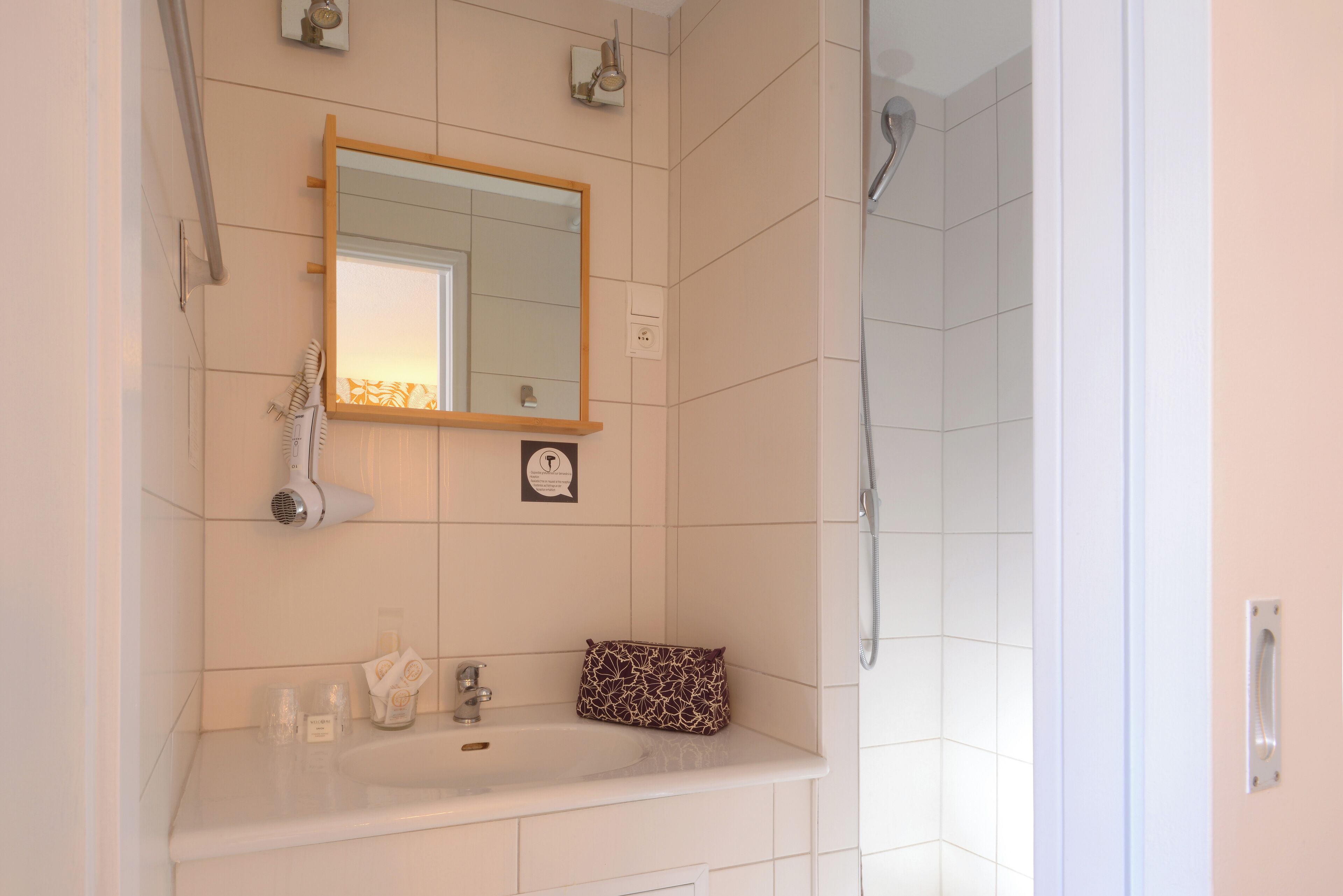 A bathroom with a sink, mirror, and shower.