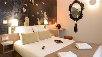 Una cama bien hecha con almohadas, una mesita de noche con una lámpara, un espejo y una pared con un mural de temática natural.