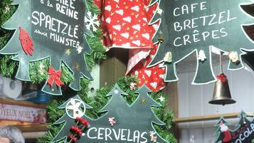 Esposizione festosa con cartelli a lavagna che elencano cibi come 'Bouchée à la Reine', 'Bretzel Crêpes' e 'Cervelas'.