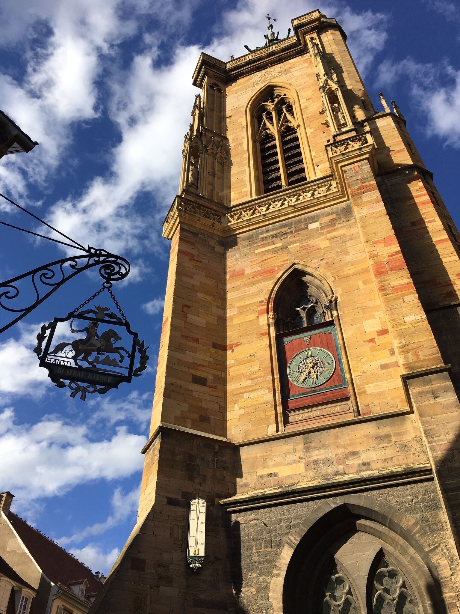 Una torre histórica con un reloj y un cartel con escudo.