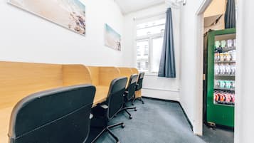 A conference room with a long table, black chairs, and a green vending machine.