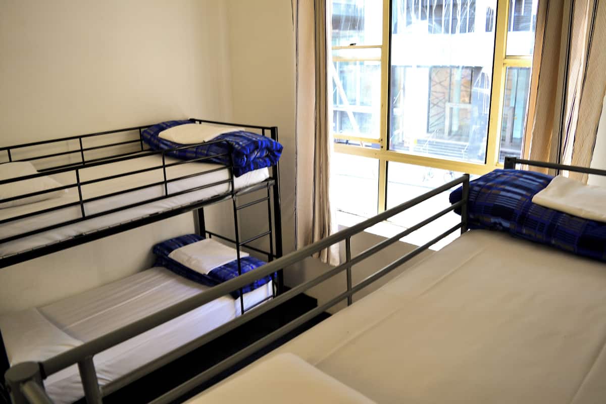 A dormitory-style room with bunk beds and a large window.