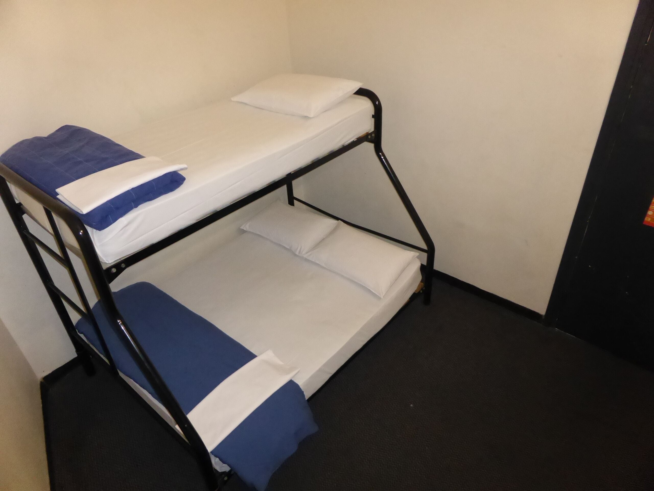 A bunk bed with two levels, each with a pillow and a blue blanket.