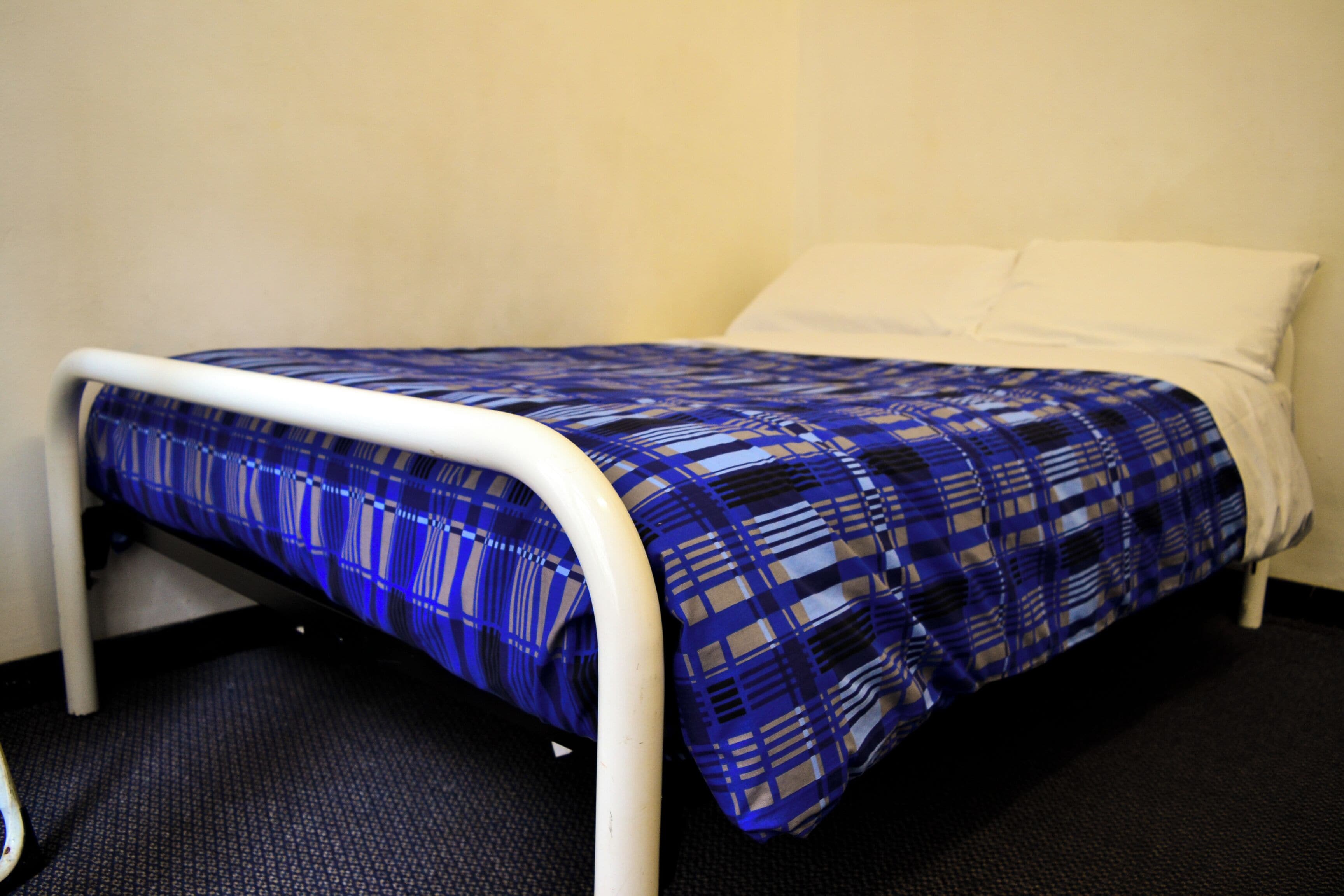A bed with a blue and white checkered bedspread and white pillows.