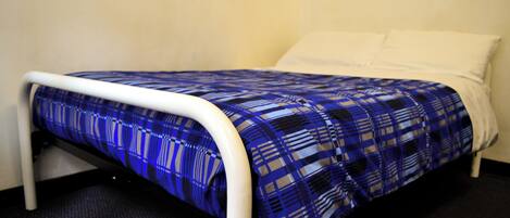A bed with a blue and white checkered bedspread and white pillows.