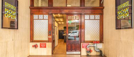 A double door entrance with a 'Now Open' sign, a fire hydrant, and a hydrant booster valve.