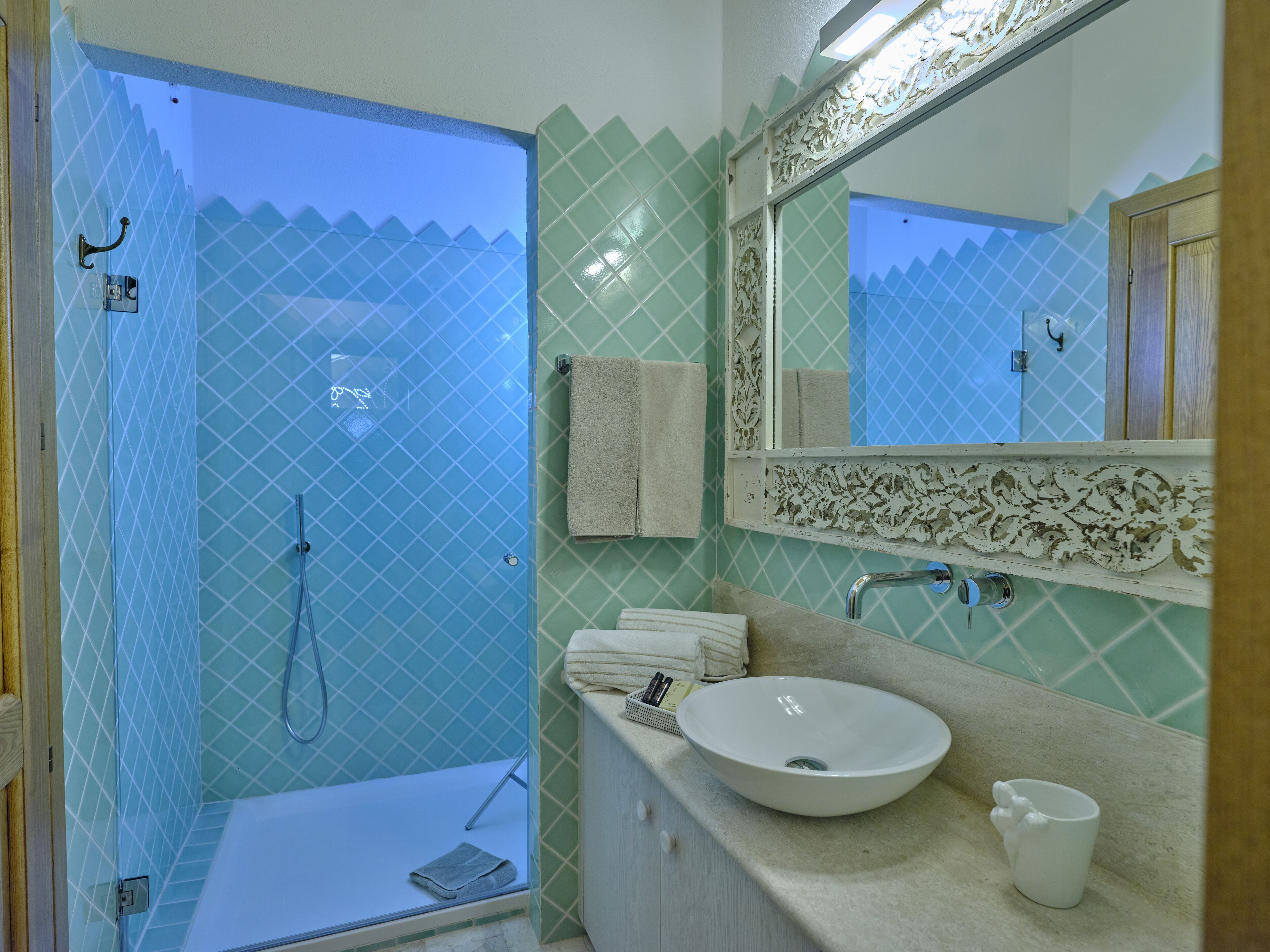 A bathroom with a glass-enclosed shower, a sink, a mirror, and a towel rack.
