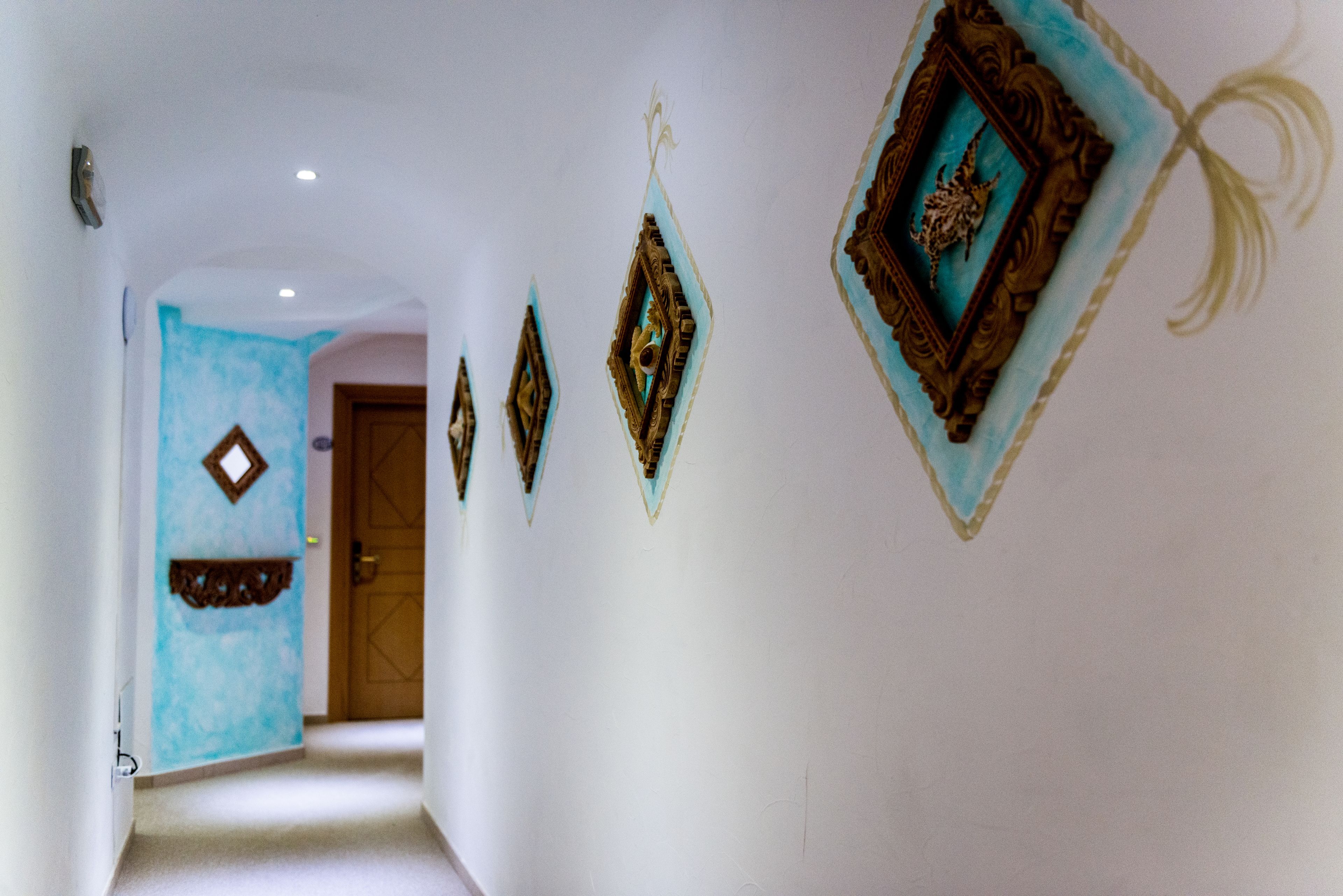 Un pasillo con arte decorativo en la pared y una pared de acento azul.
