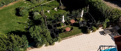 An aerial view of a rooftop pool area with a swing set, seating, and a small garden.