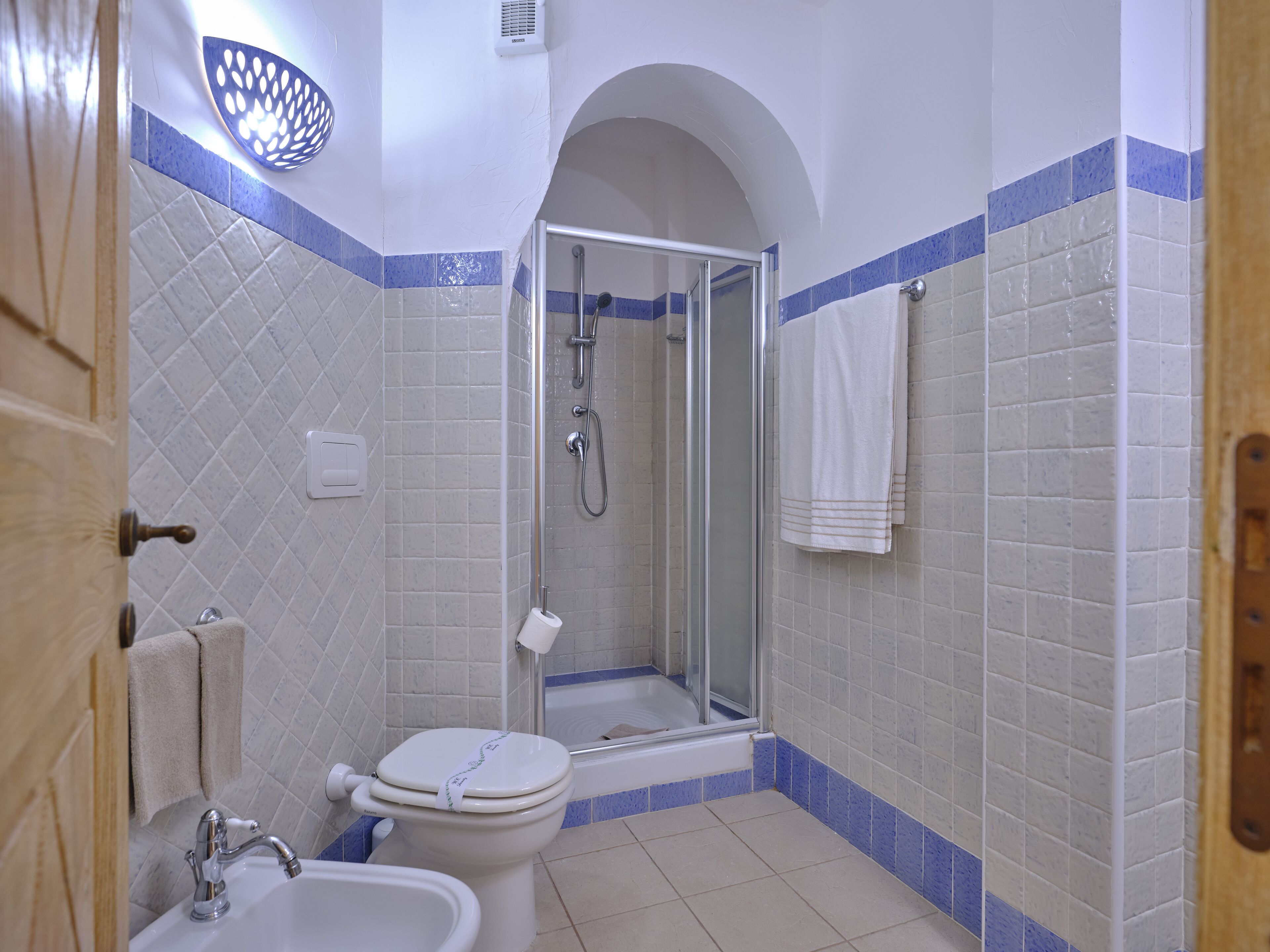 A bathroom with a toilet, sink, shower, and a towel rack.