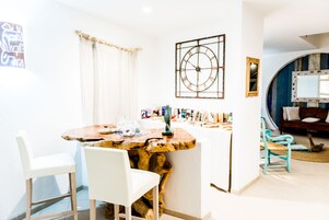 Un comedor con una mesa de madera, sillas blancas, un reloj de pared y un espejo.