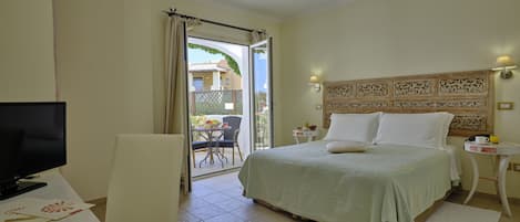A hotel room with a bed, a TV, a table with a lamp, and a view of the outside.