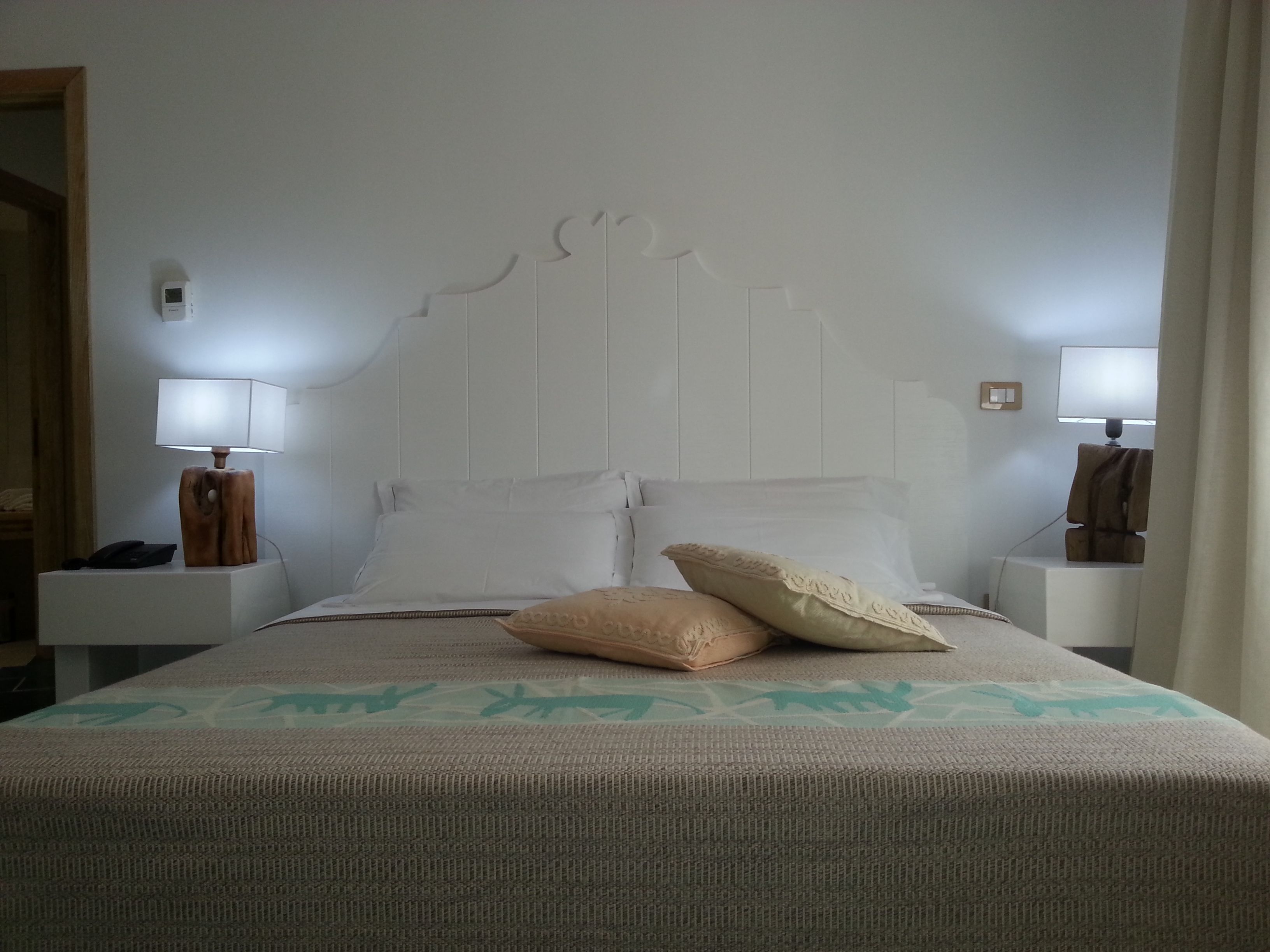 Une chambre d’hôtel comprenant un lit, deux tables de chevet et deux lampes fixées au mur.