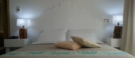 Une chambre d’hôtel comprenant un lit, deux tables de chevet et deux lampes fixées au mur.