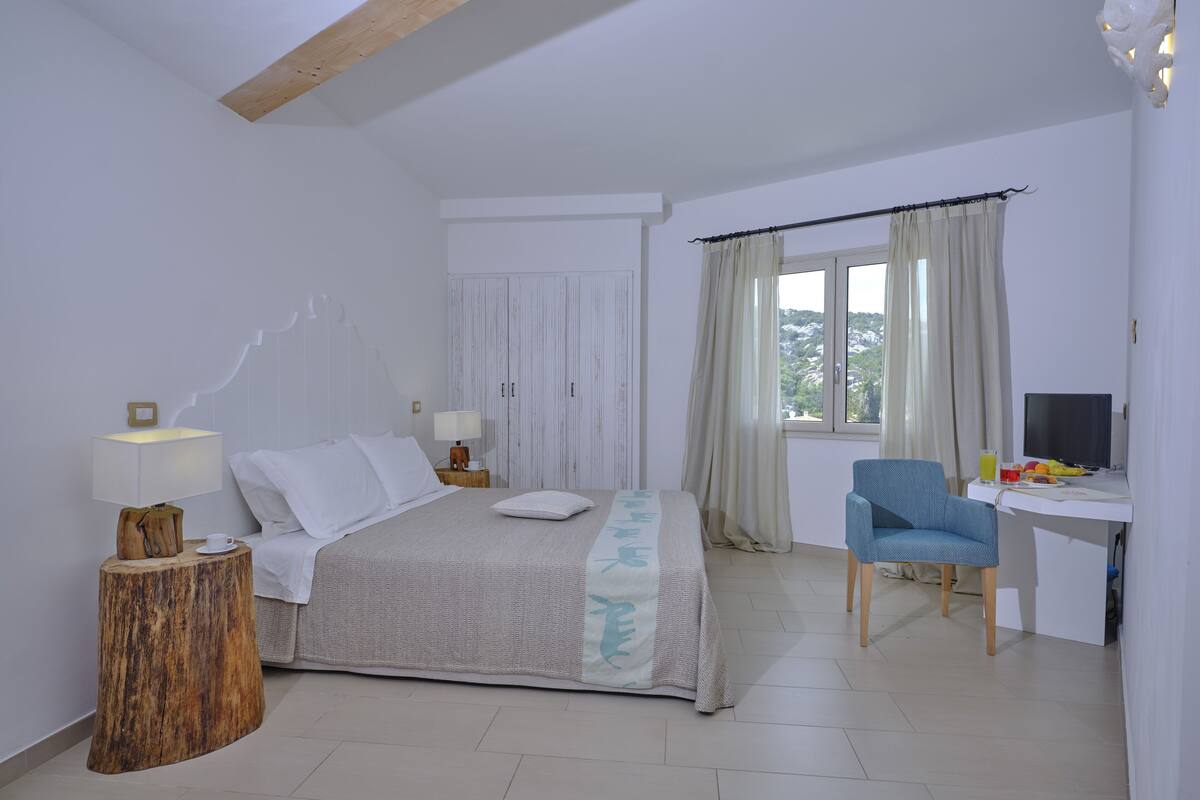 Un dormitorio con cama, mesita de noche, lámpara y escritorio con silla.