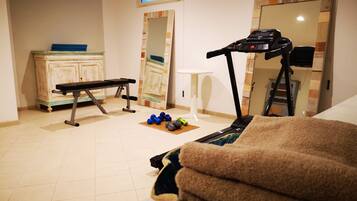 Una palestra in casa con tapis roulant, panca e manubri.