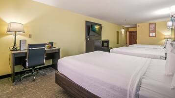 A hotel room with two beds, a desk with a chair, a TV, and a coffee machine.