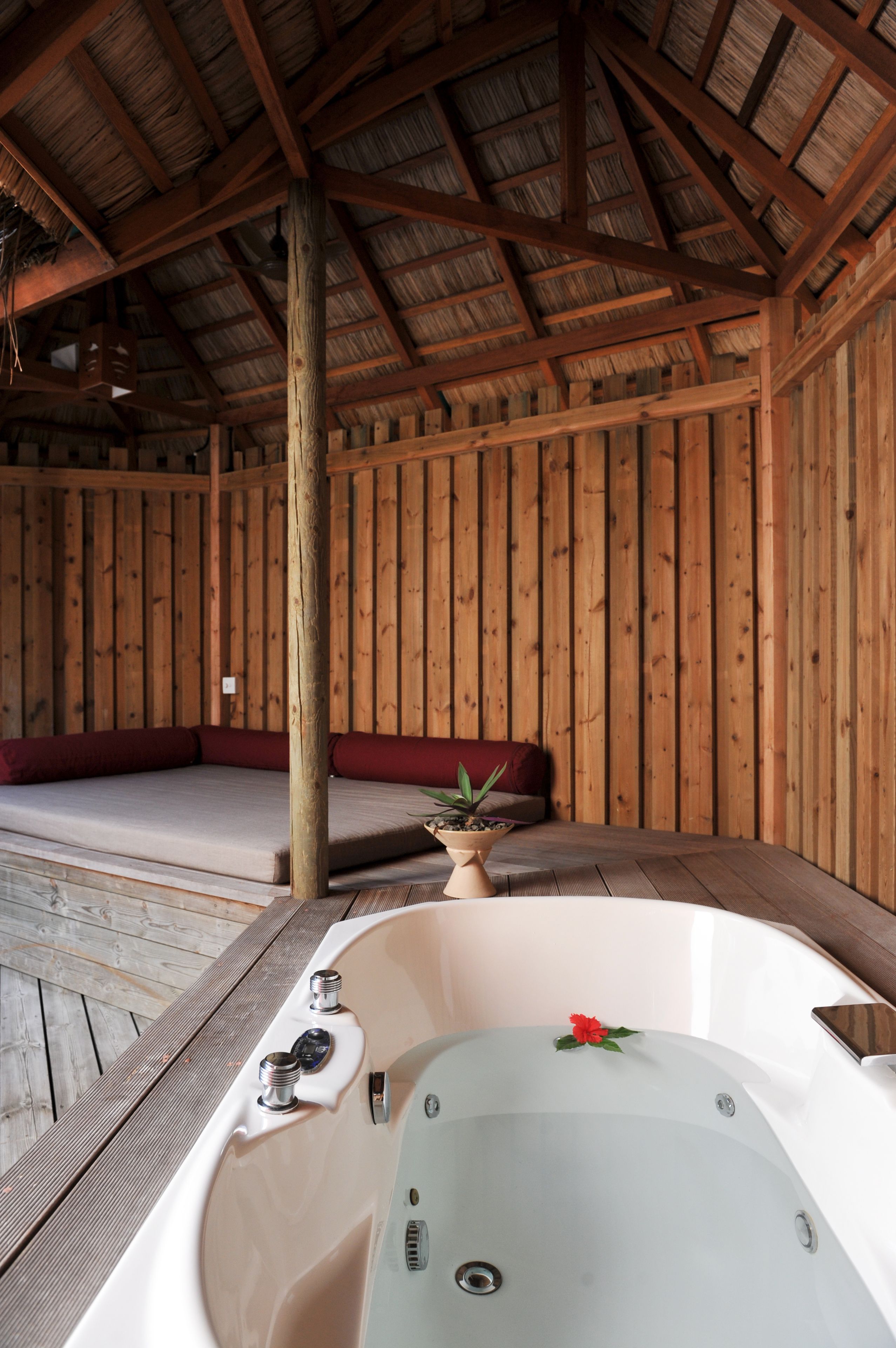 Une cabane en bois dotée d’un bain à remous, de murs en bois et d’un banc.