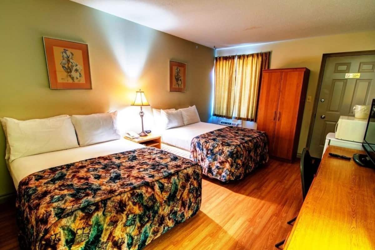 Ein Hotelzimmer mit zwei Betten, einem Schreibtisch, einer Lampe und einem Kleiderschrank.