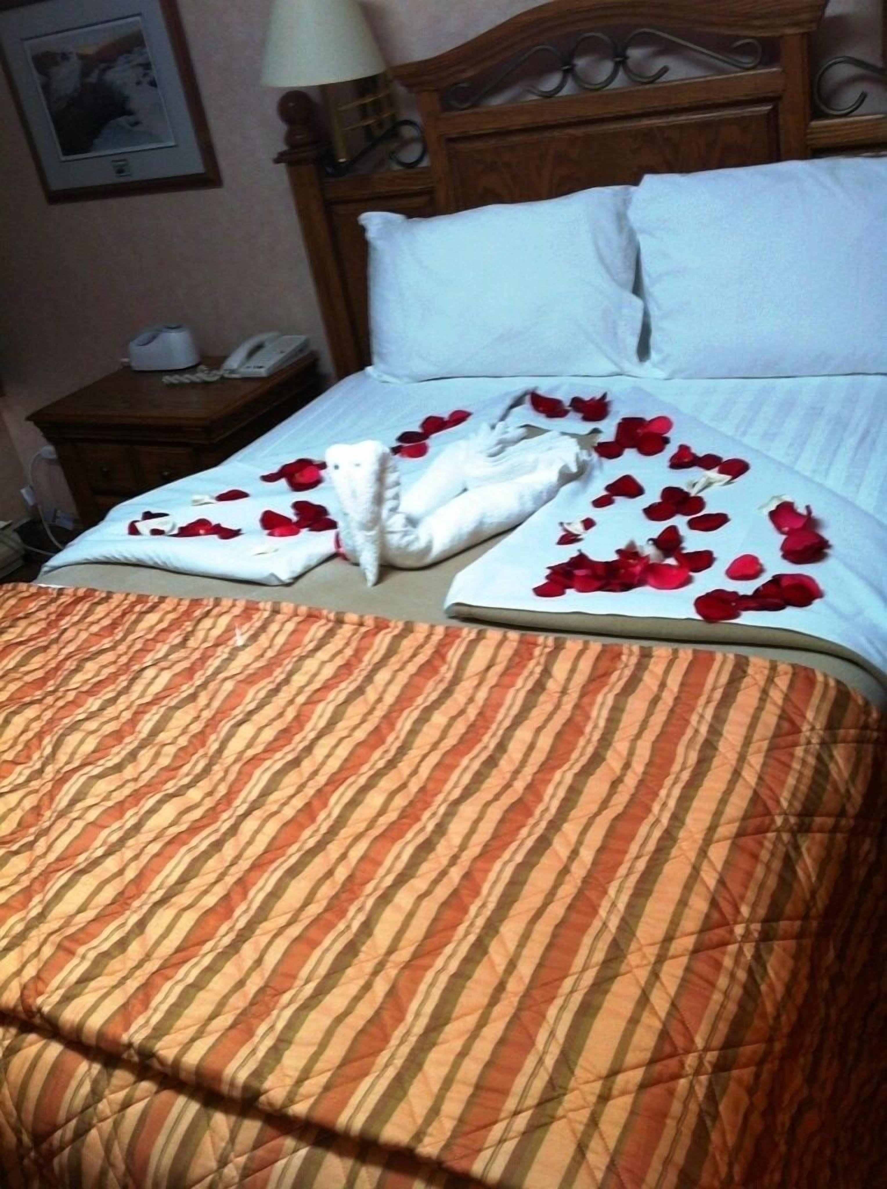 Un letto con una coperta a righe, un cuscino bianco e un asciugamano bianco piegato.
