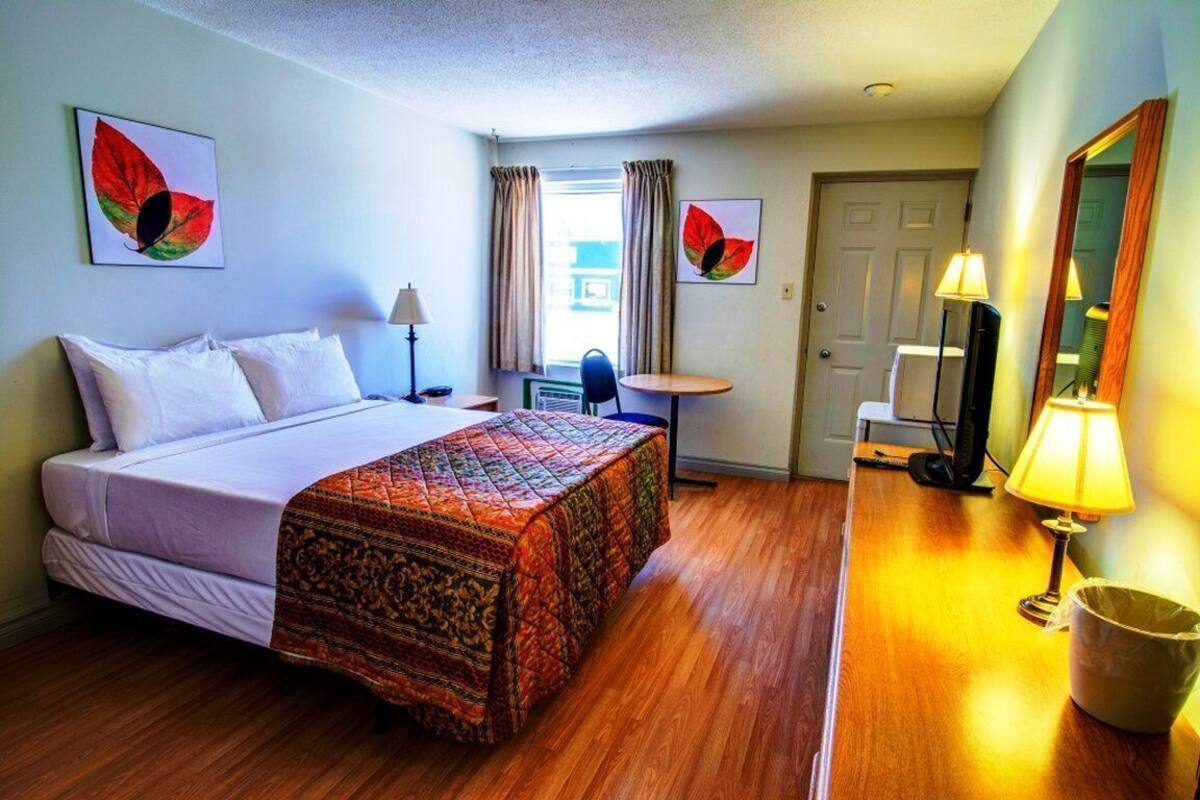 Ein Hotelzimmer mit Bett, Schreibtisch, Stuhl, Lampe und Spiegel.