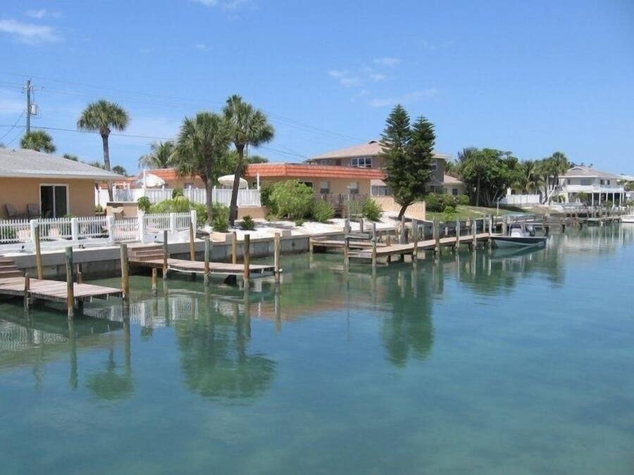 Propiedad frente al mar con muelle, aguas cristalinas y edificios residenciales.