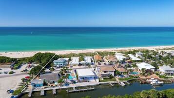 Vista aérea de una zona costera con puerto deportivo, playa y edificios residenciales.