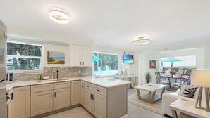 Una cocina moderna con una isla central, armarios blancos y una zona de comedor con mesa y sillas.