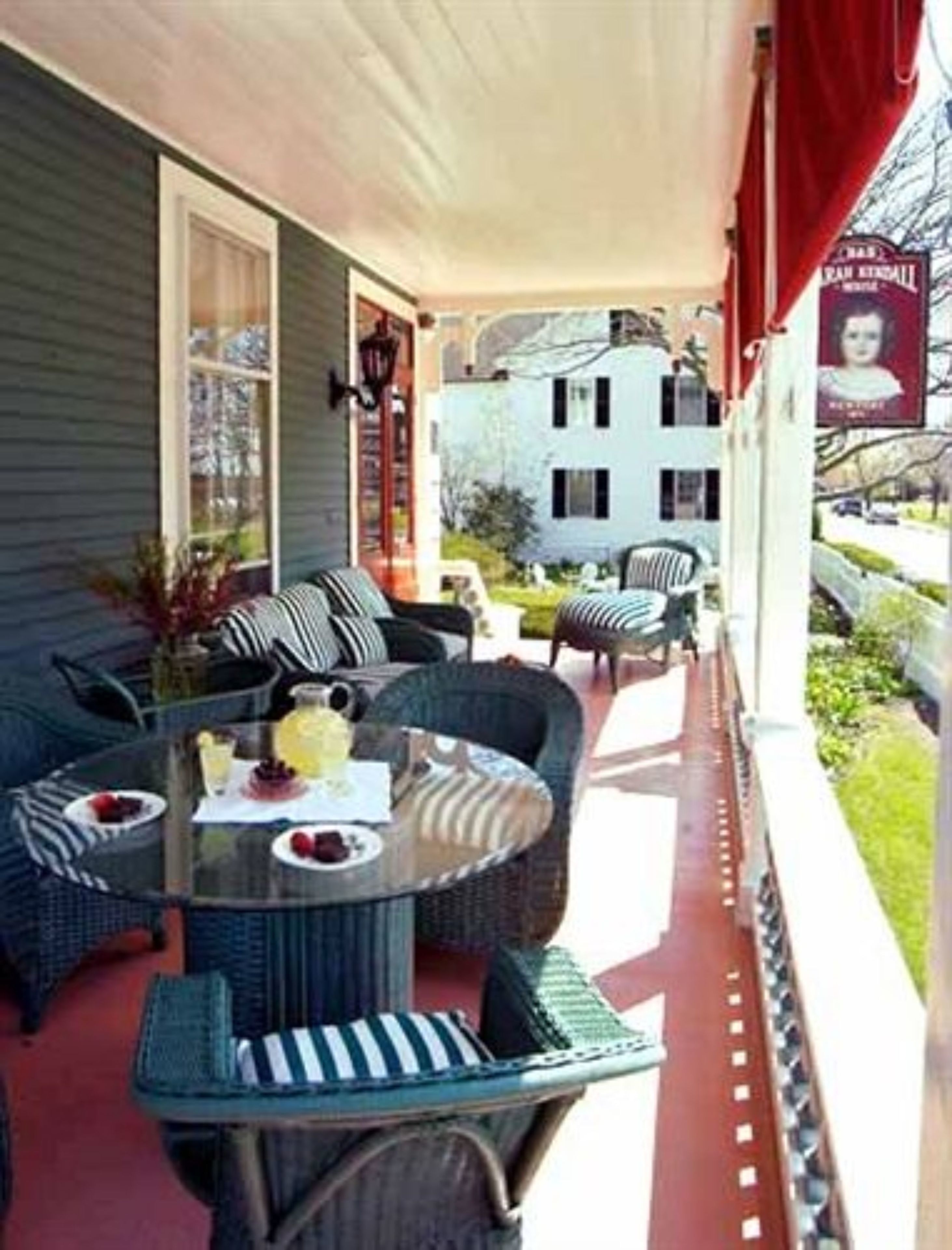 A covered porch with wicker furniture, a glass table, and a red awning.